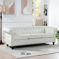 Canapé 3 places Chesterfield en similicuir blanc avec accoudoirs roulés, clous décoratifs argentés et pieds en bois